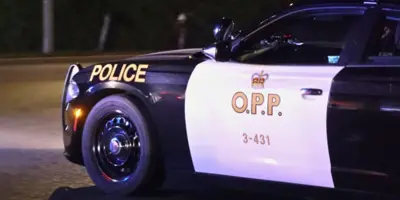 Side of a black and white OPP cruiser parked on the road at night