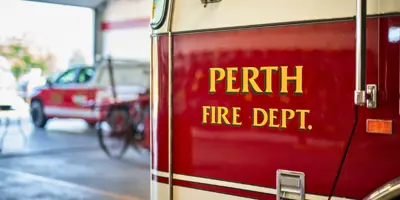 Close up of door on fire truck with lettering that says "Perth Fire Deptartment", parked inside the fire hall