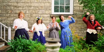 Group in period costumes standing in a garden and cheering