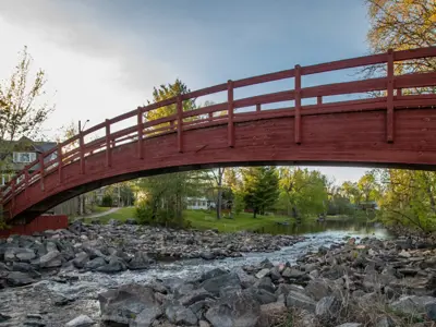 Red wood pedestrian bridge over a rocky riverbed