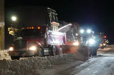 Snow removal vehicles clearing snow banks at night