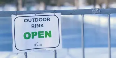 Sign on metal fence in front of rink that says outdoor rink open