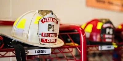 White fire helmet on top of red rack. Helmet says Perth Fire P1 Fire Chief Trevor Choffe